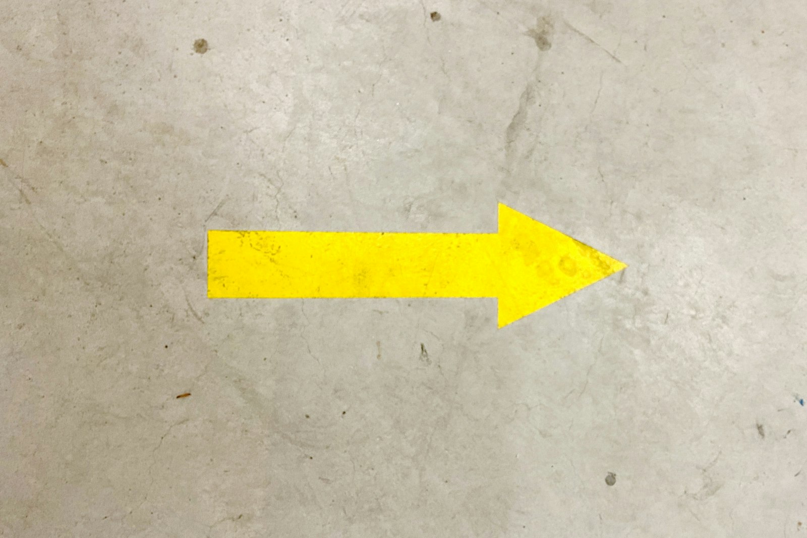 Gelber Pfeil auf grauem Betonboden
