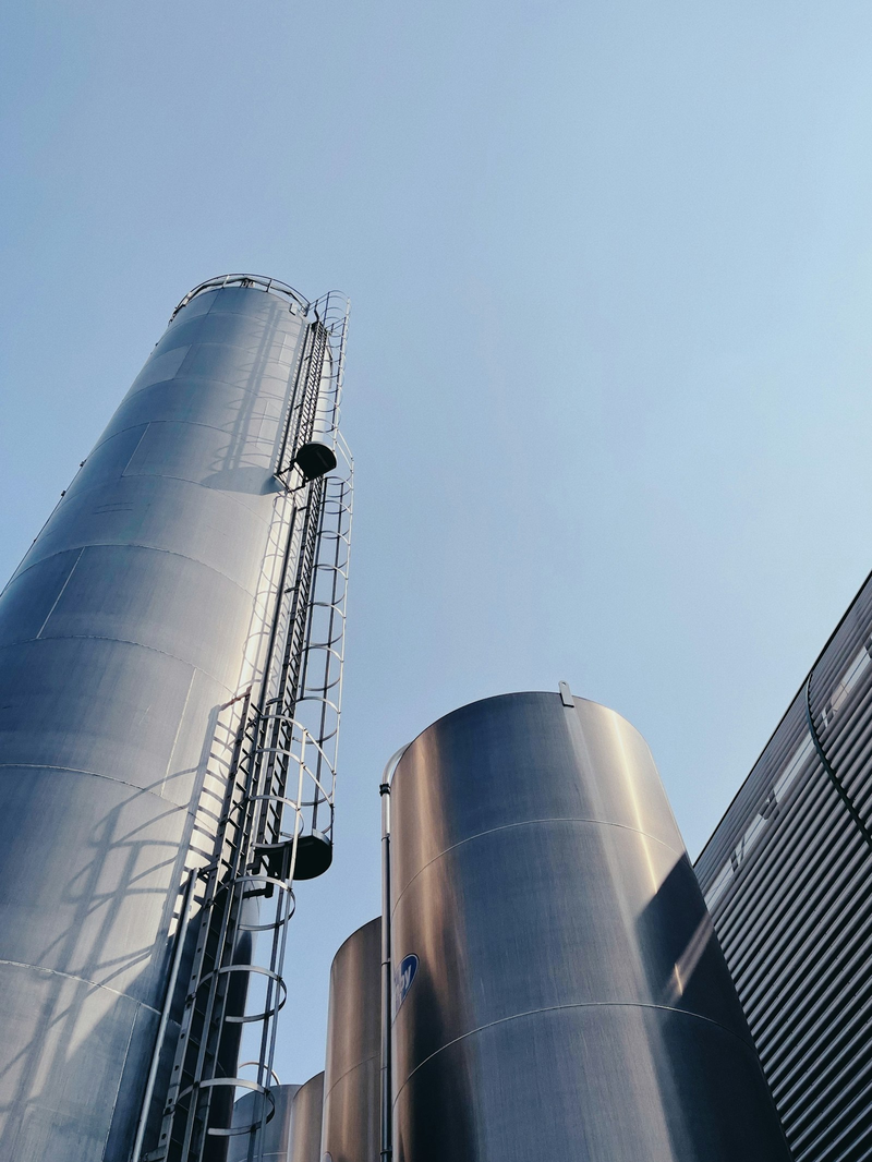 Hohe Metallsilos mit Leitern vor blauem Himmel