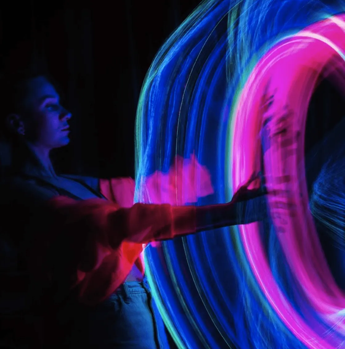 Person mit Neonringen aus blauem und magentafarbenem Licht