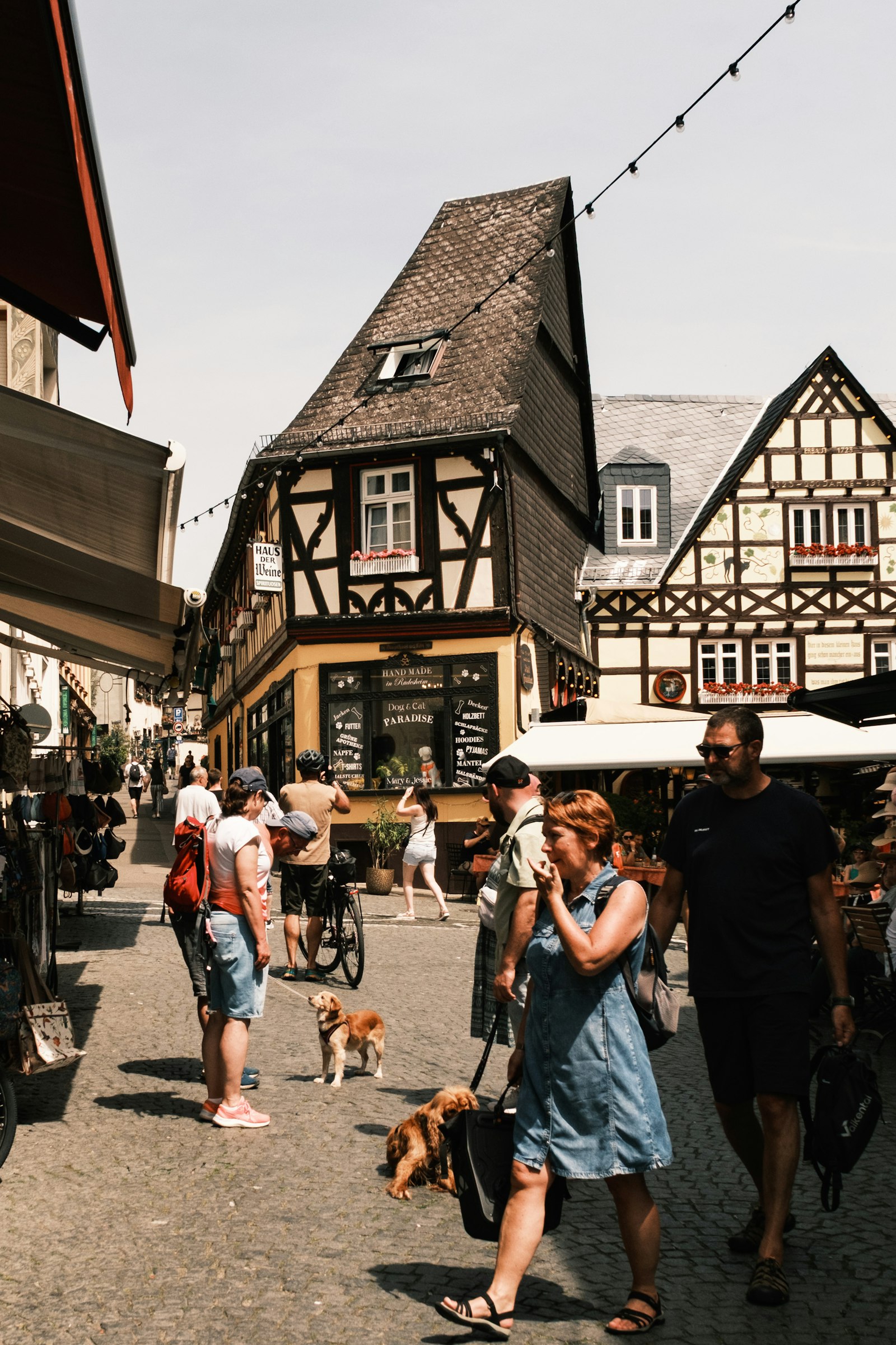 Sonnige Altstadtstraße mit Fachwerkhäusern, Passanten und kleinen Geschäften