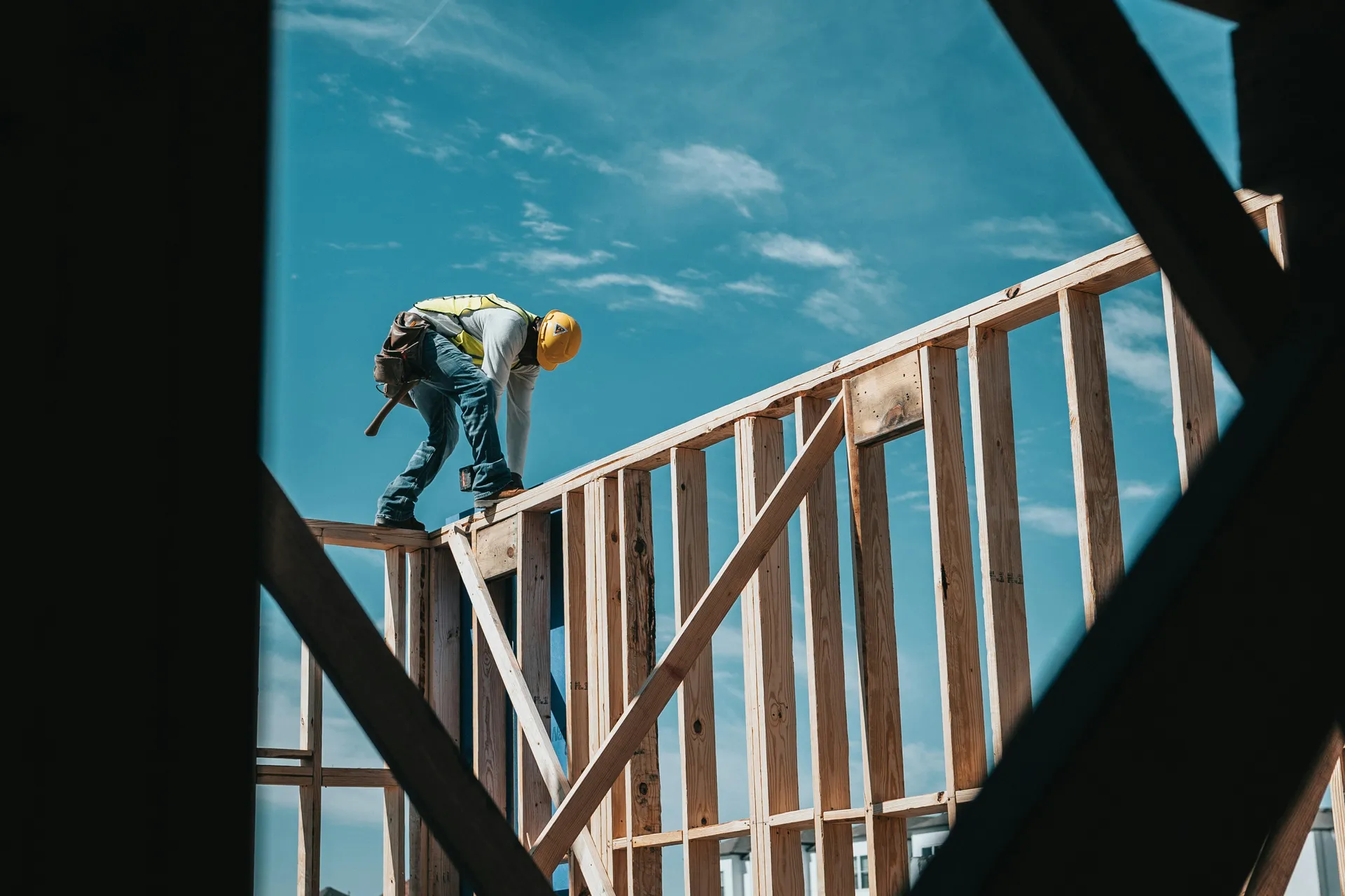 Handwerker mit Schutzhelm arbeitet auf einem Holzständerwerk