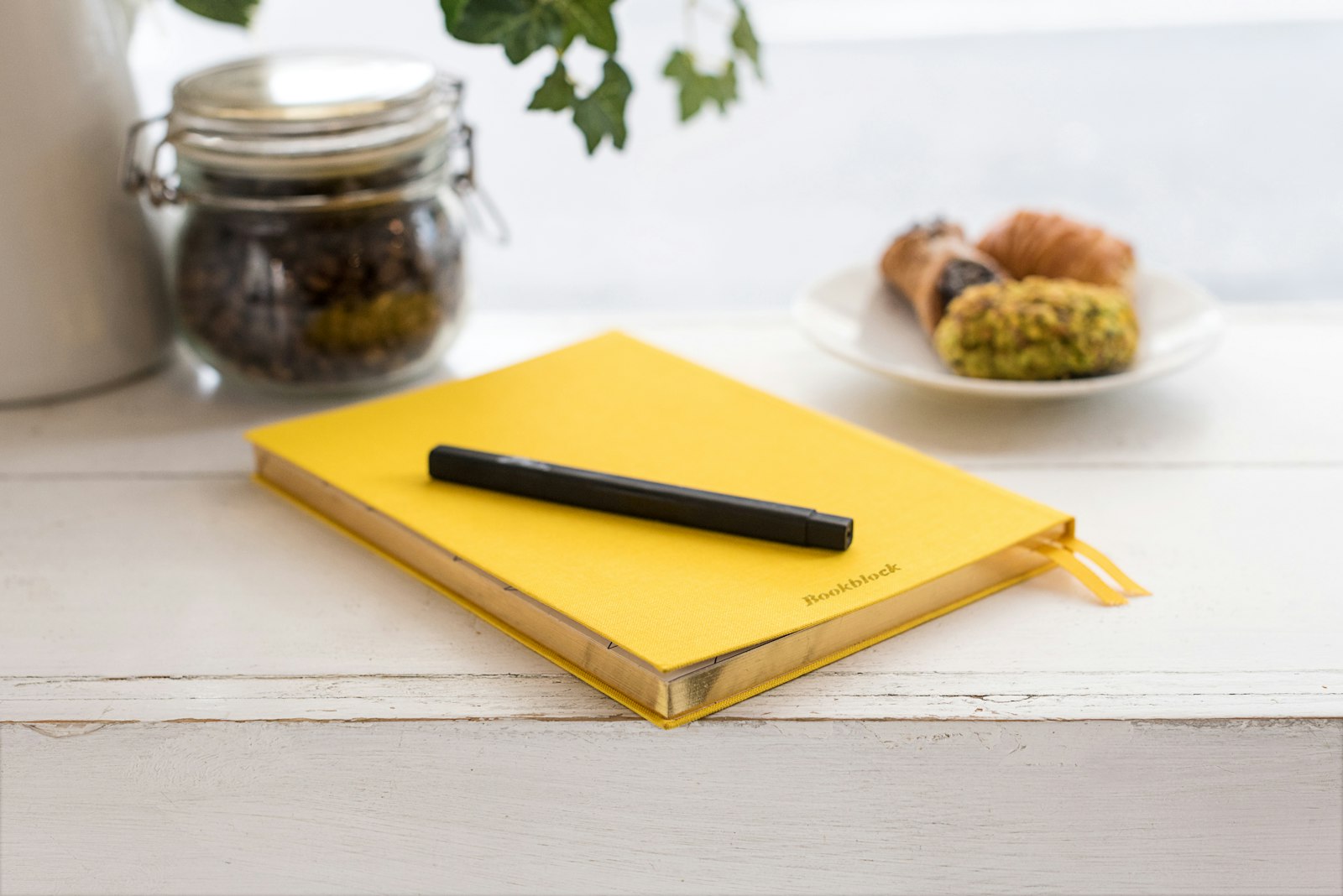 Gelbes Notizbuch mit Stift auf einem hellen Tisch