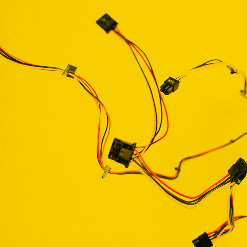 Bunte Elektronik-Kabel mit Steckverbindern vor gelbem Hintergrund
