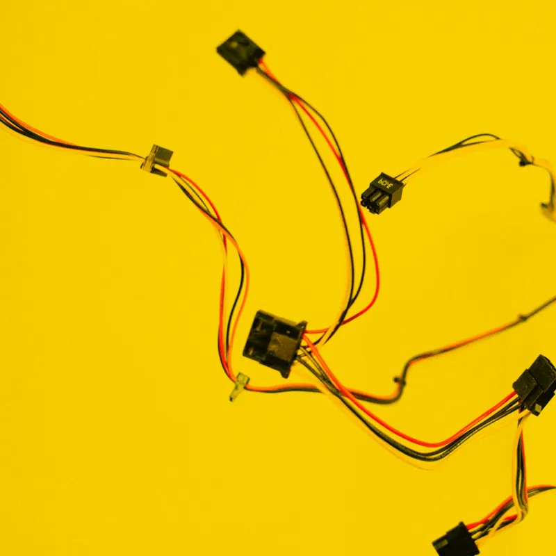 Bunte Elektronik-Kabel mit Steckverbindern vor gelbem Hintergrund