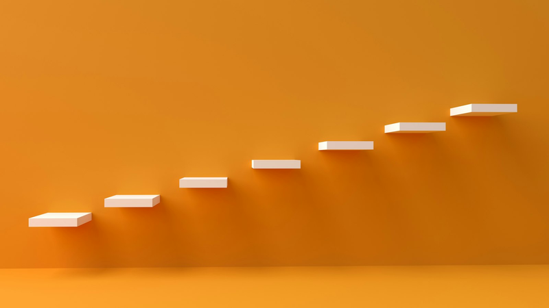 Weiße Stufen, die an einer orangefarbenen Wand nach oben führen