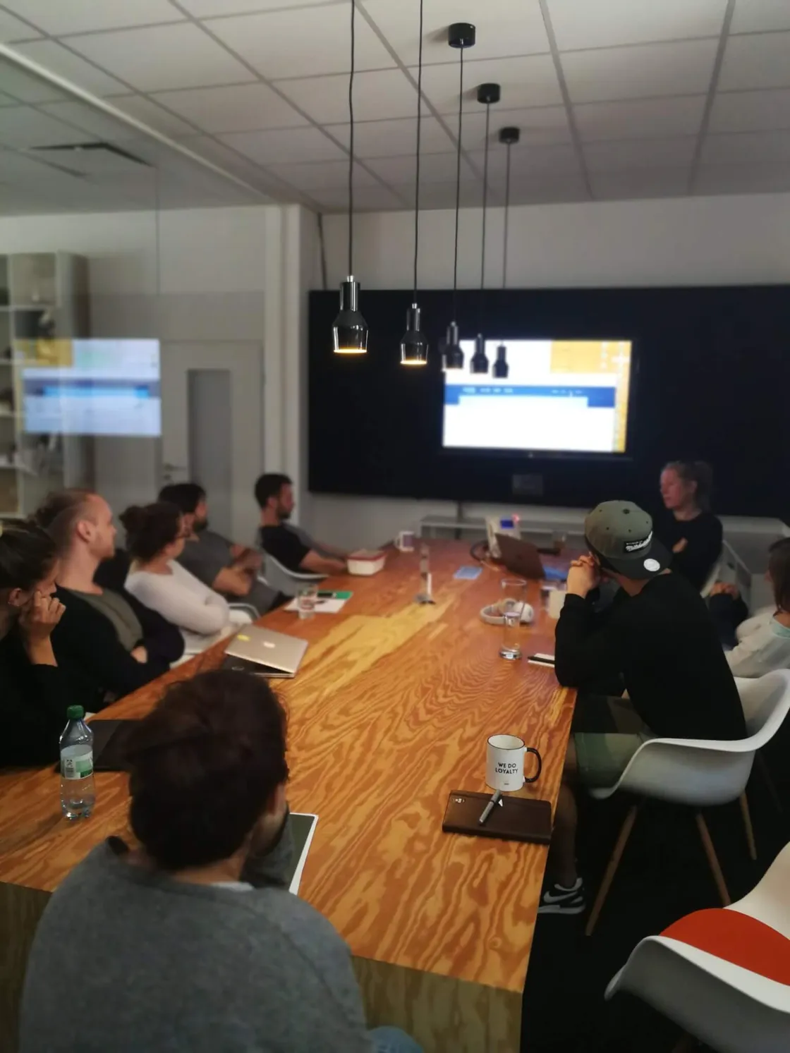 Teammeeting im modernen Konferenzraum mit Holztisch und Bildschirmpräsentation