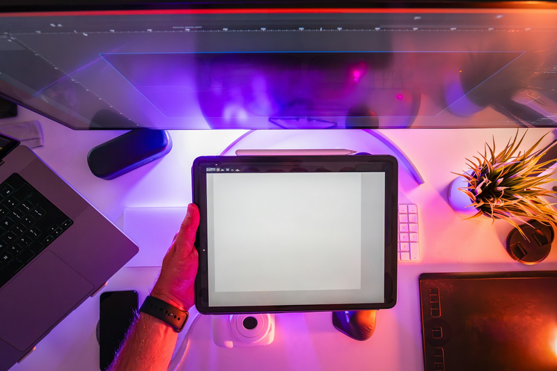 Person hält ein Tablet vor einen Computerbildschirm