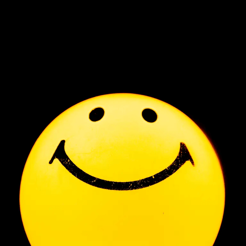 Leuchtender gelber Smiley vor schwarzem Hintergrund