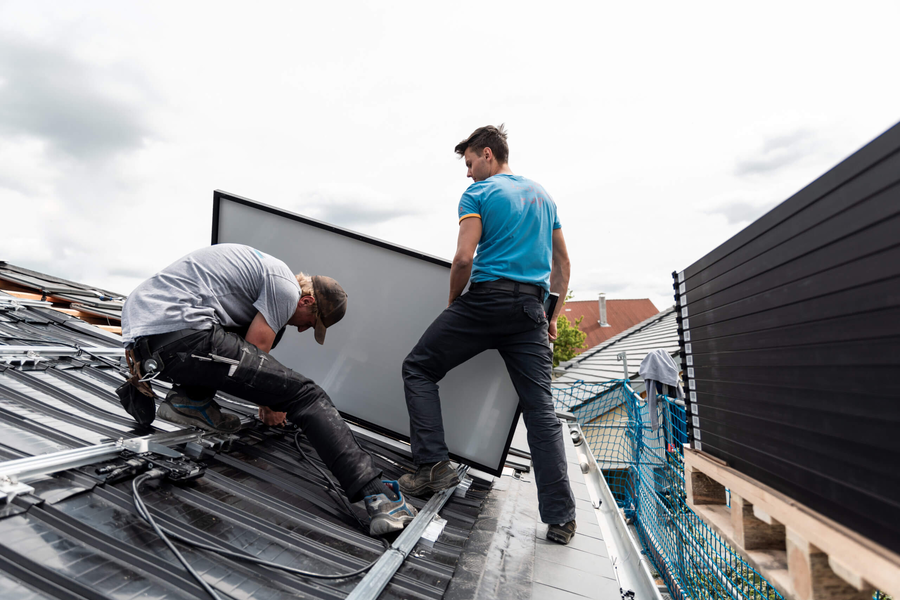 Monteure montieren Solarmodul auf Schrägdach
