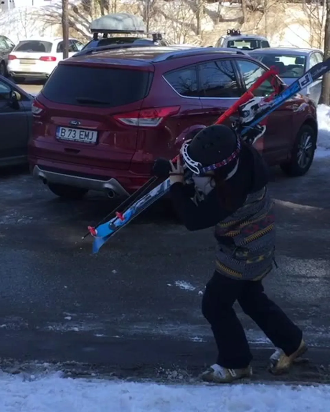 Teammitglied trägt Ski über den verschneiten Parkplatz