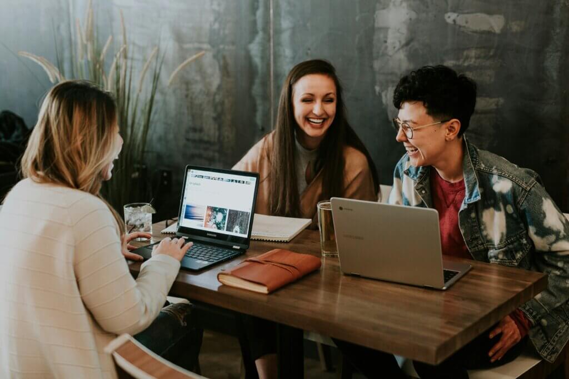 Drei junge Leute arbeiten gemeinsam an Laptops im Café