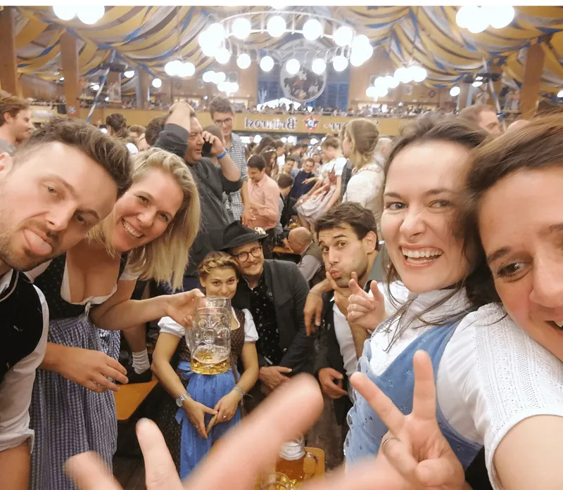 Oktoberfest-Selfie: Freunde im Festzelt mit Bierkrügen und Trachten