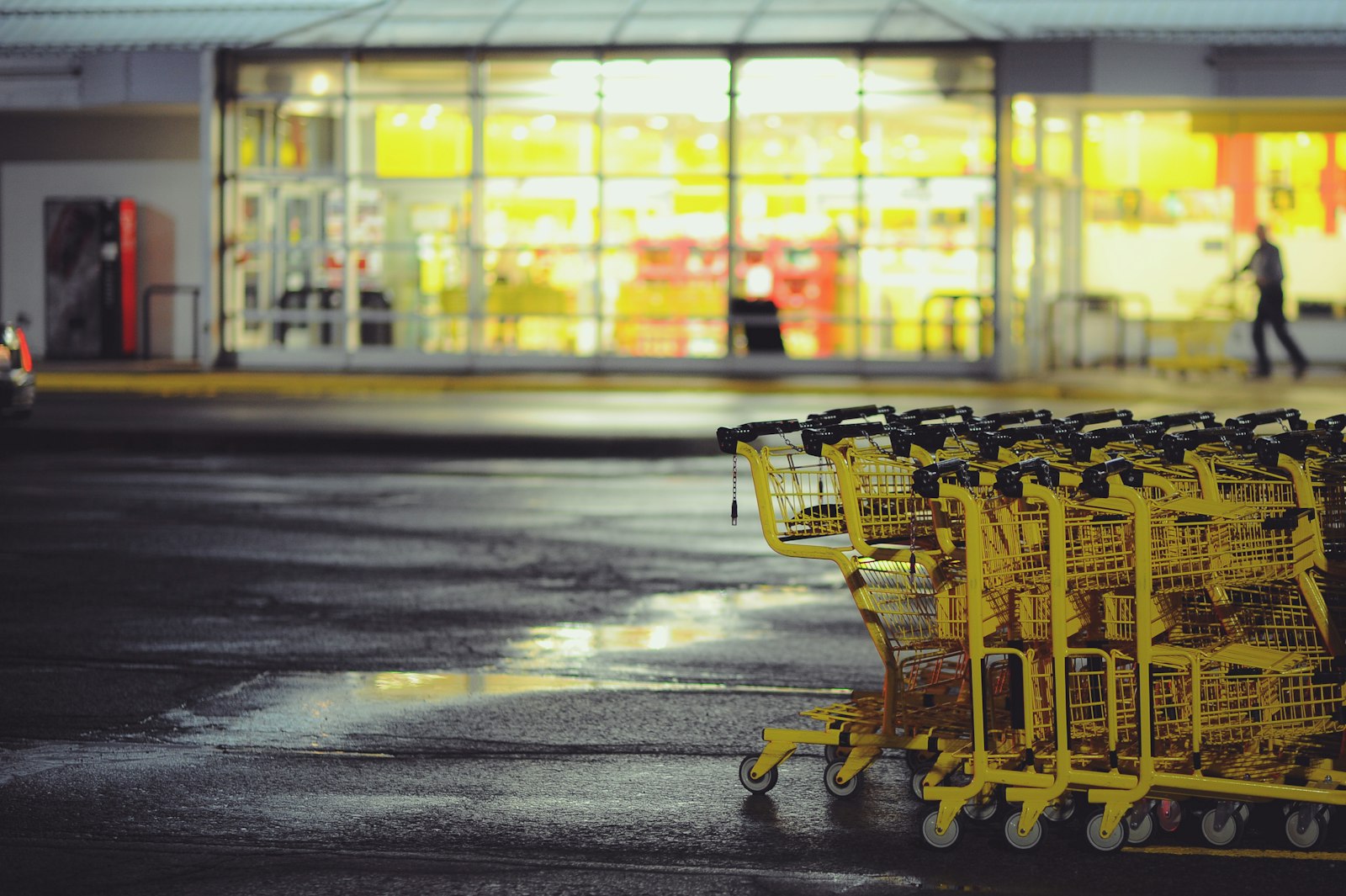 Gelbe Einkaufswagen vor einem beleuchteten Supermarkt