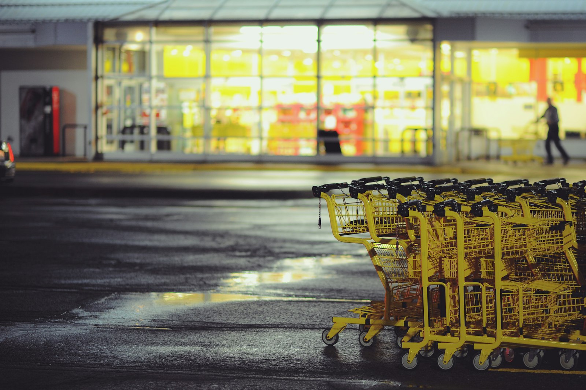 Gelbe Einkaufswagen vor einem beleuchteten Supermarkt