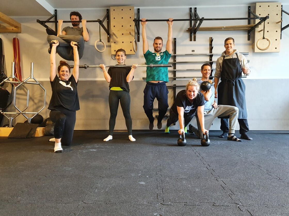 Sieben Personen im Functional-Studio beim Gruppenfitness, freundliche Teamatmosphäre, Trainingsgeräte im Hintergrund