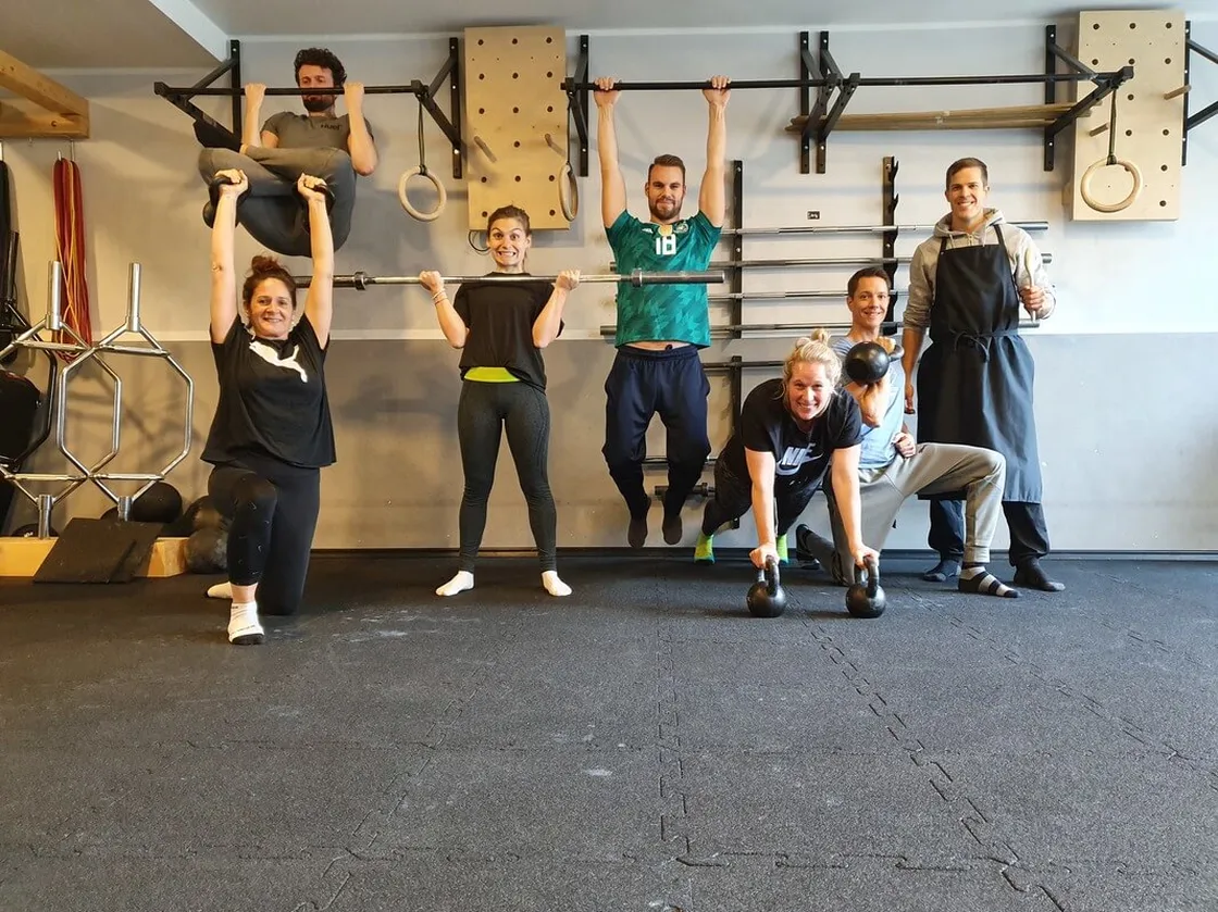 Sieben Personen im Functional-Studio beim Gruppenfitness, freundliche Teamatmosphäre, Trainingsgeräte im Hintergrund