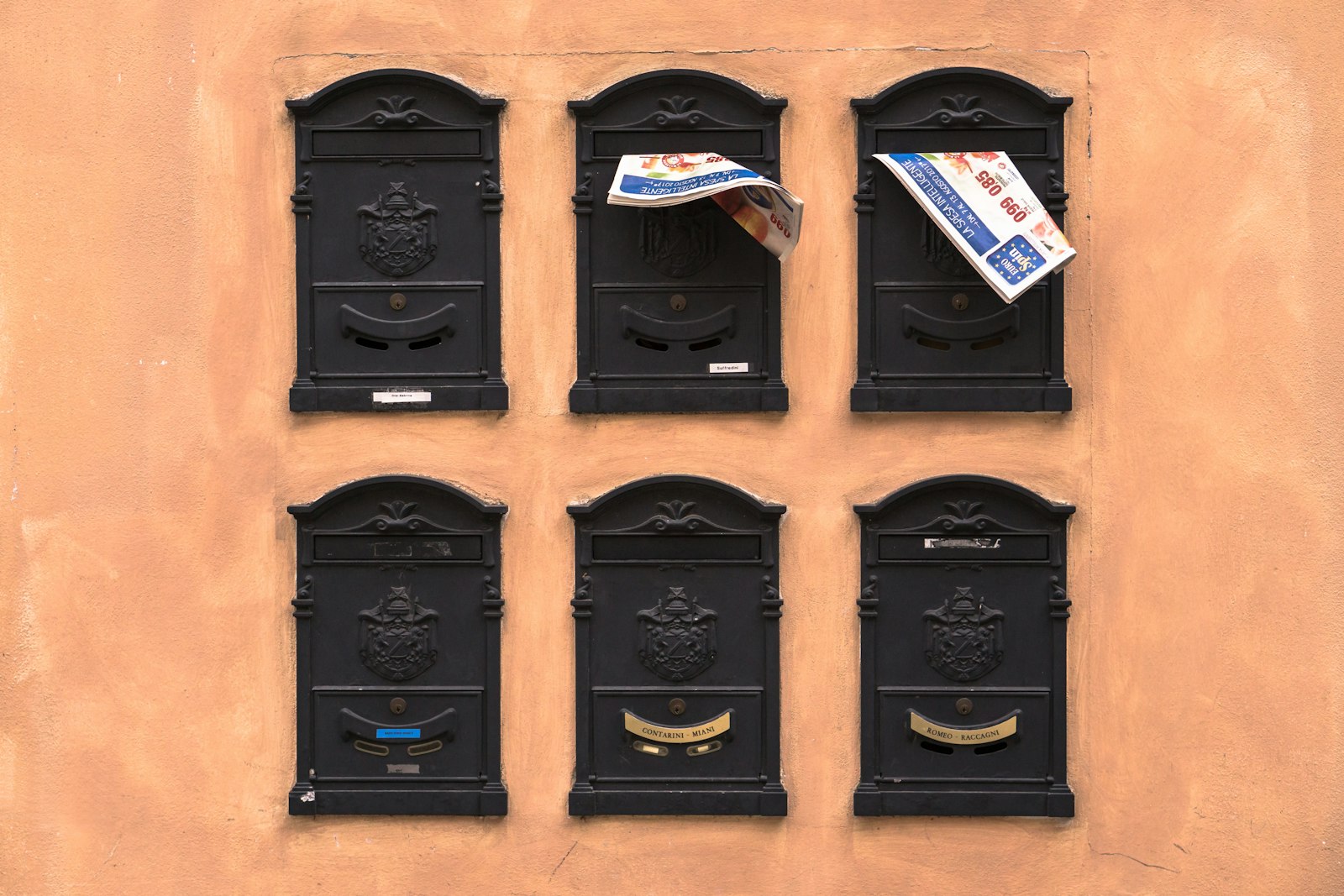 Schwarze Briefkästen an einer orangefarbenen Wand