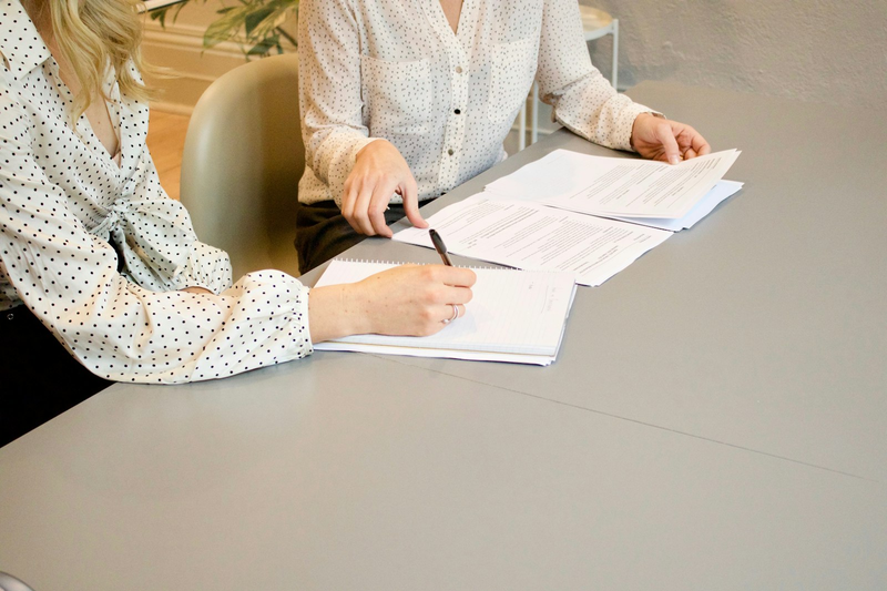 Frau unterschreibt ein Dokument am Tisch