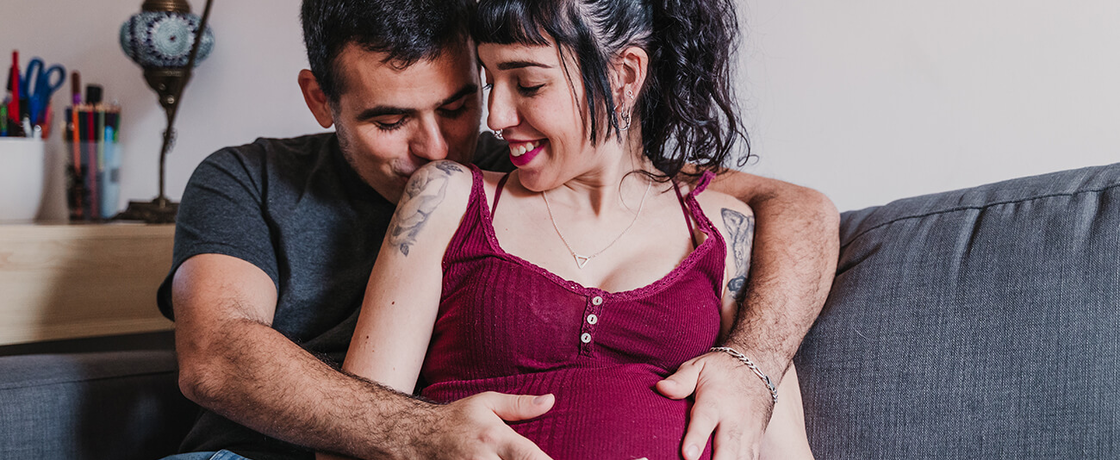 Liebevolles Paar umarmt Babybauch auf Sofa