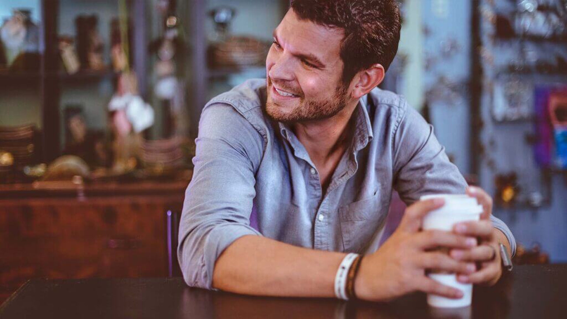 Lächelnder Mann mit Kaffeebecher in einem Café