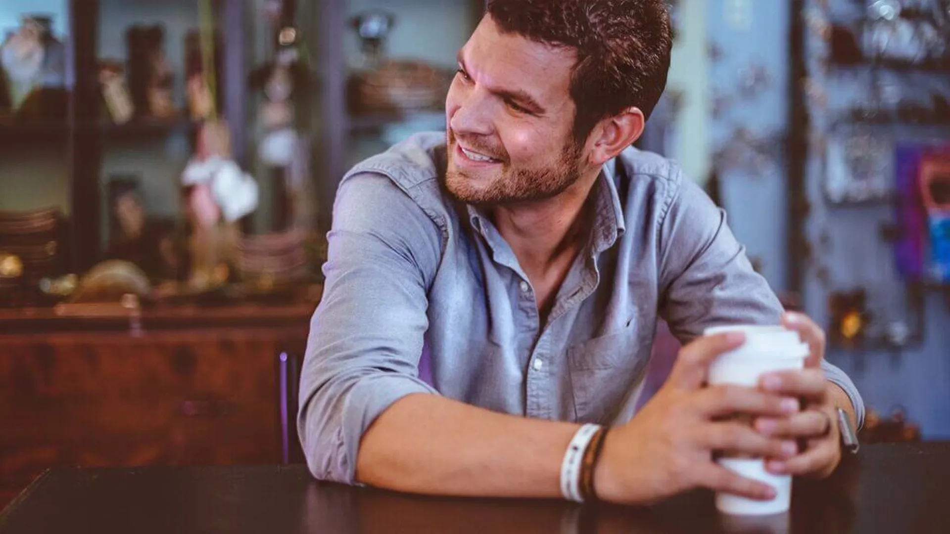 Lächelnder Mann mit Kaffeebecher in einem Café