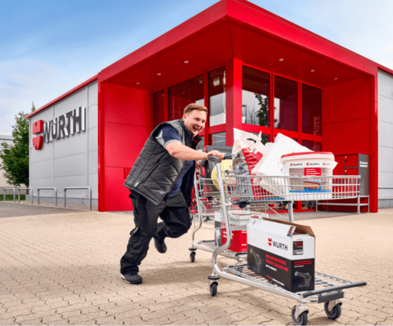 Mitarbeiter schiebt volle Einkaufswagen vor einer Filiale