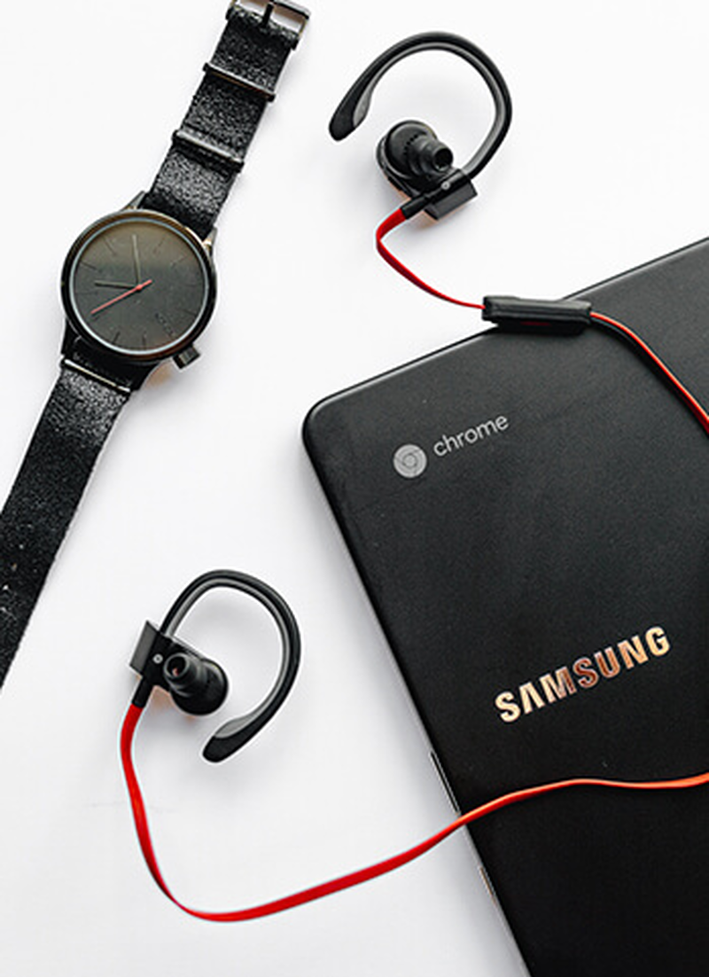 Samsung Chromebook, schwarze Armbanduhr und rote In-Ears