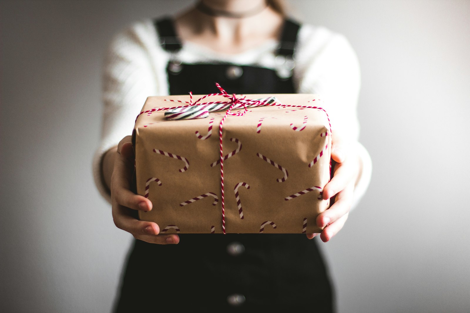 Hände überreichen ein verpacktes Geschenk