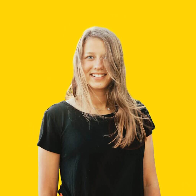 Porträt von Carina Kartenhäuser, die freundlich in die Kamera lächelt und einen modernen Hintergrund hat