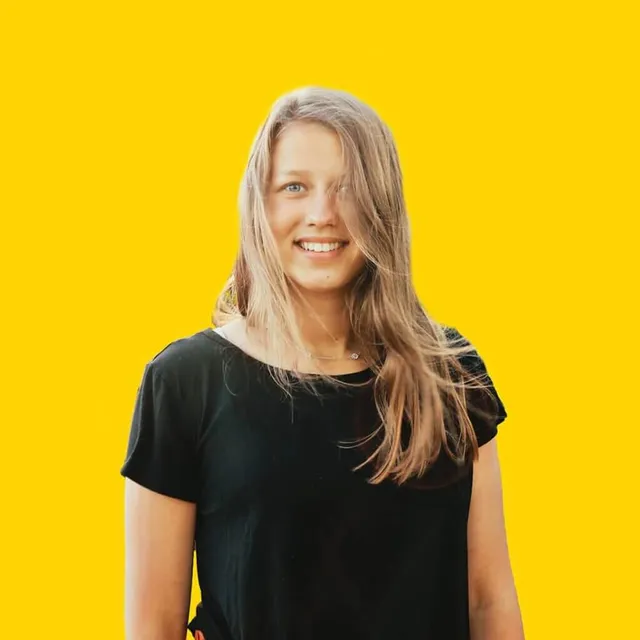 Porträt von Carina Kartenhauser, die freundlich in die Kamera lächelt und einen modernen Hintergrund hat
