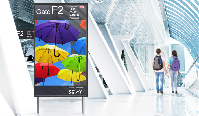 Helle Flughafenpassage mit Gate F2, bunter Schirmwerbung und zwei Reisenden unter Glasdach
