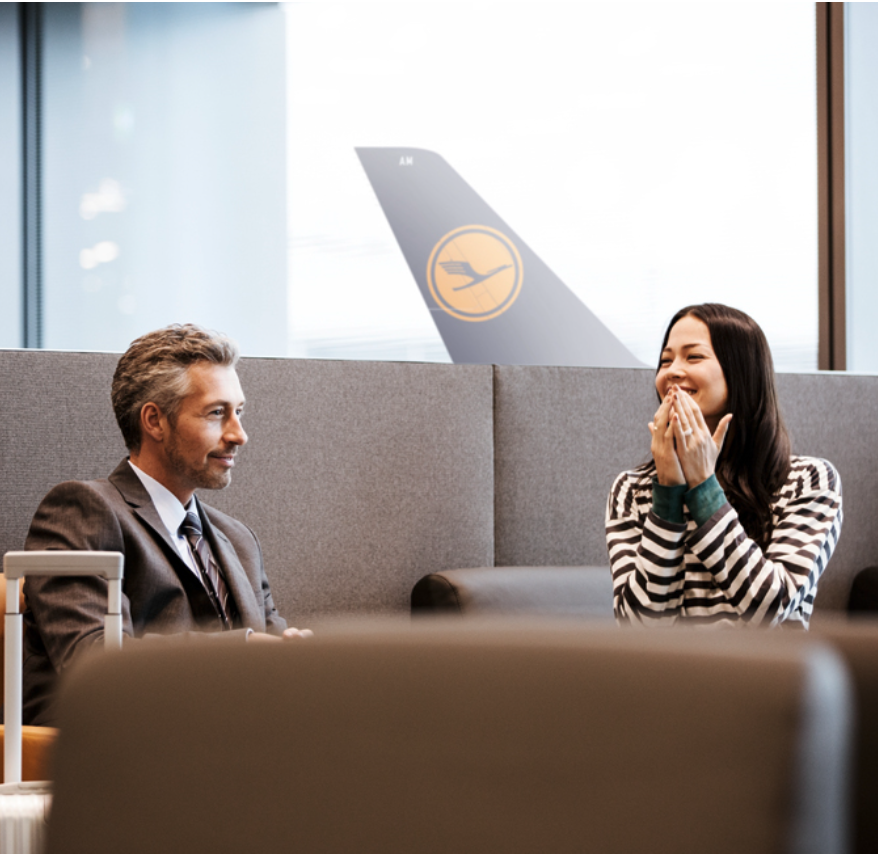 Geschäftsreisende in Flughafenlounge, Gespräch über Vorteilsprogramme für Kundenbindung