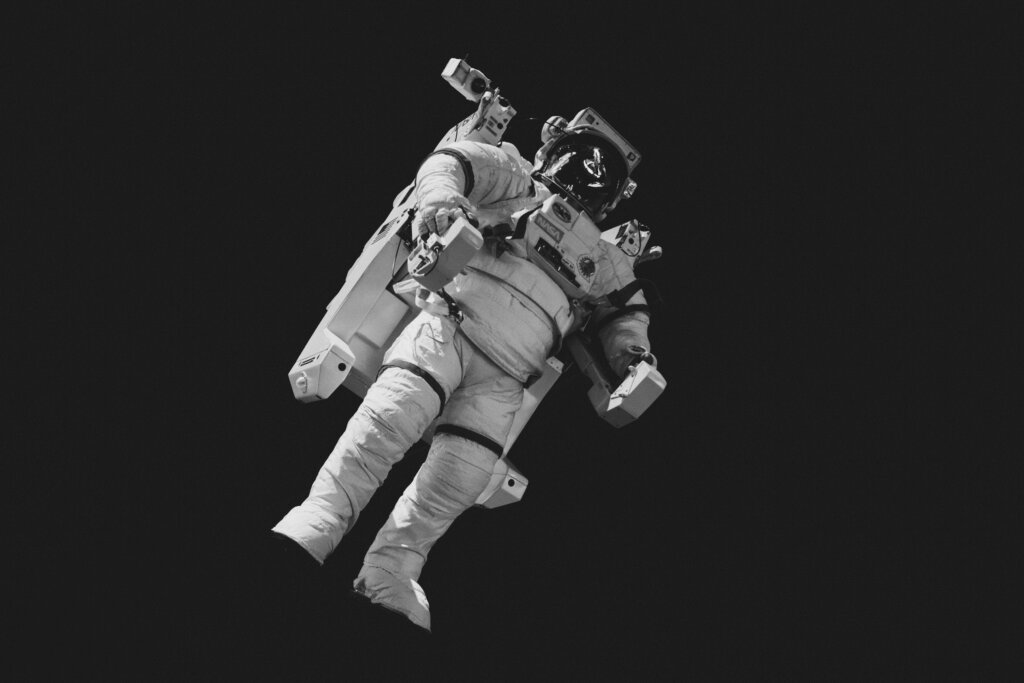 Schwereloser Astronaut im Raumanzug vor schwarzem Weltraum