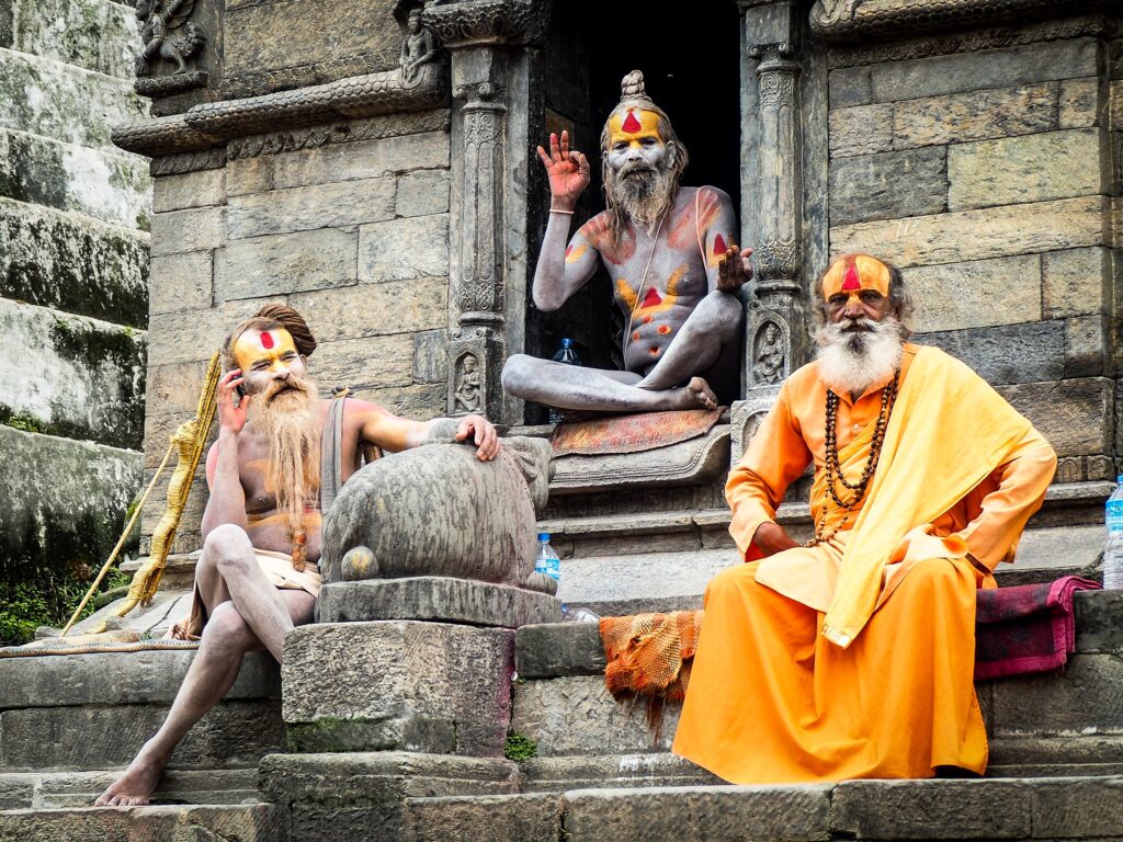 Drei Sadhus auf verwitterten Stufen, bunte Gesichtsbemalungen — kunden werben kunden