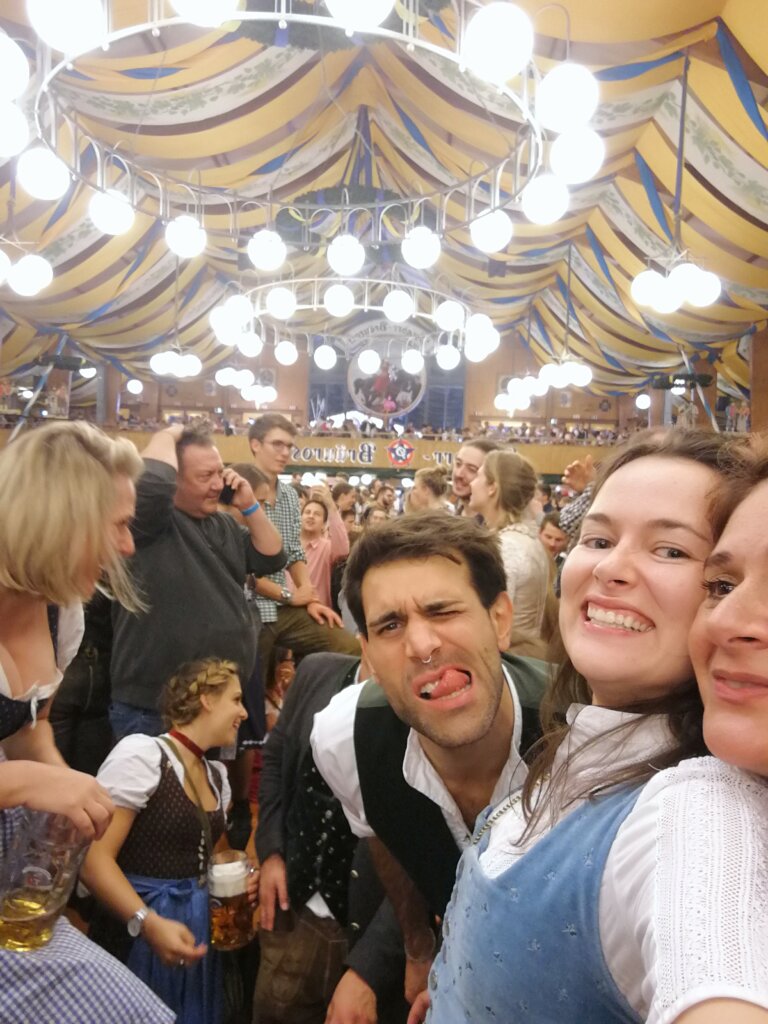 Oktoberfest-Selfie im Festzelt: lachende Freunde in Tracht mit Bierkrügen