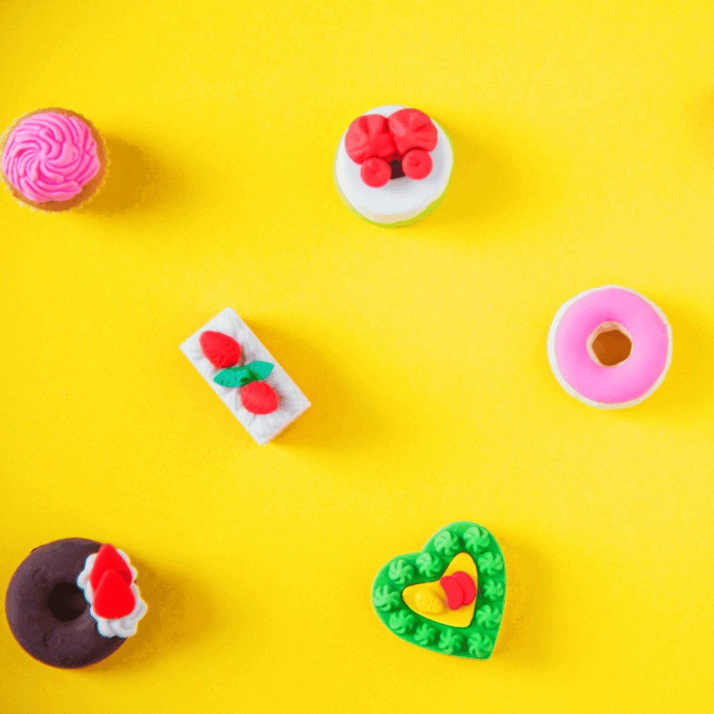 Bunte Mini-Desserts: Cupcake, Donut, Herz auf knallgelbem Hintergrund