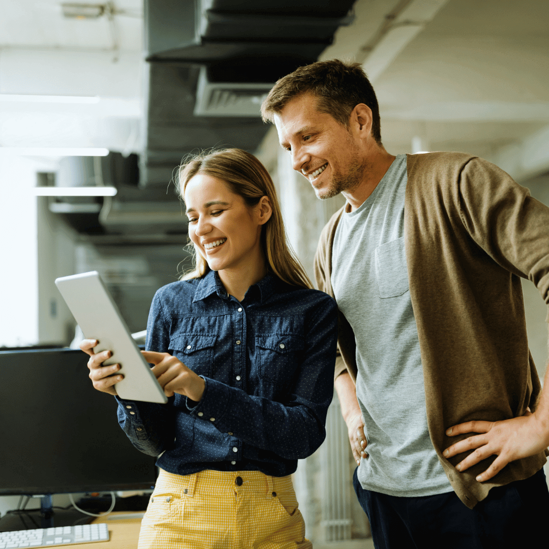 Kundenbindung steigern: Zwei Kollegen arbeiten gemeinsam am Tablet im modernen Büro.