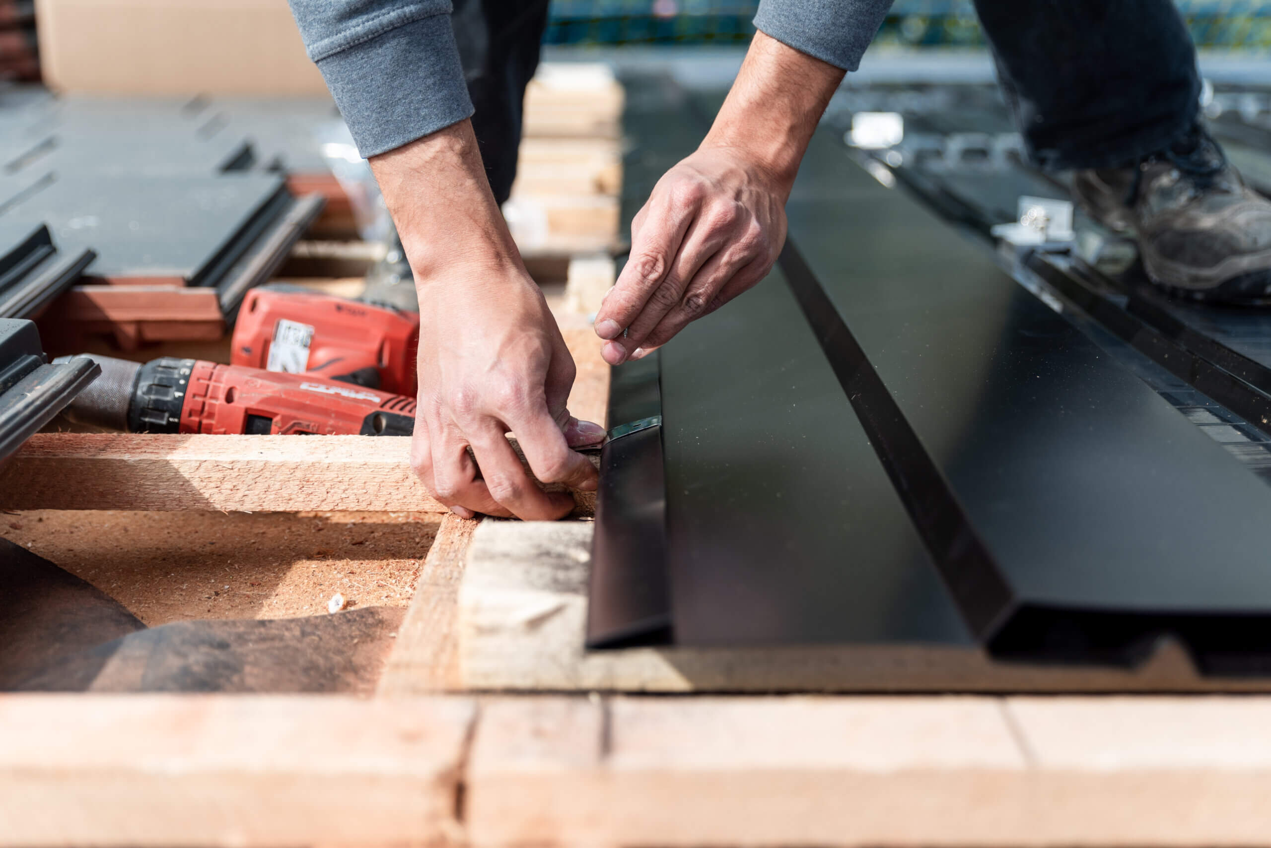 Partnerprogramm Photovoltaik für Verarbeiter: Handmontage von Metallpaneelen auf Dach