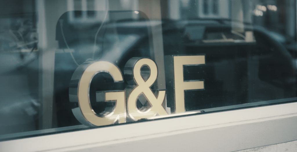 Goldenes G&F-Logo im Schaufenster mit unscharfen Stadtreflexionen