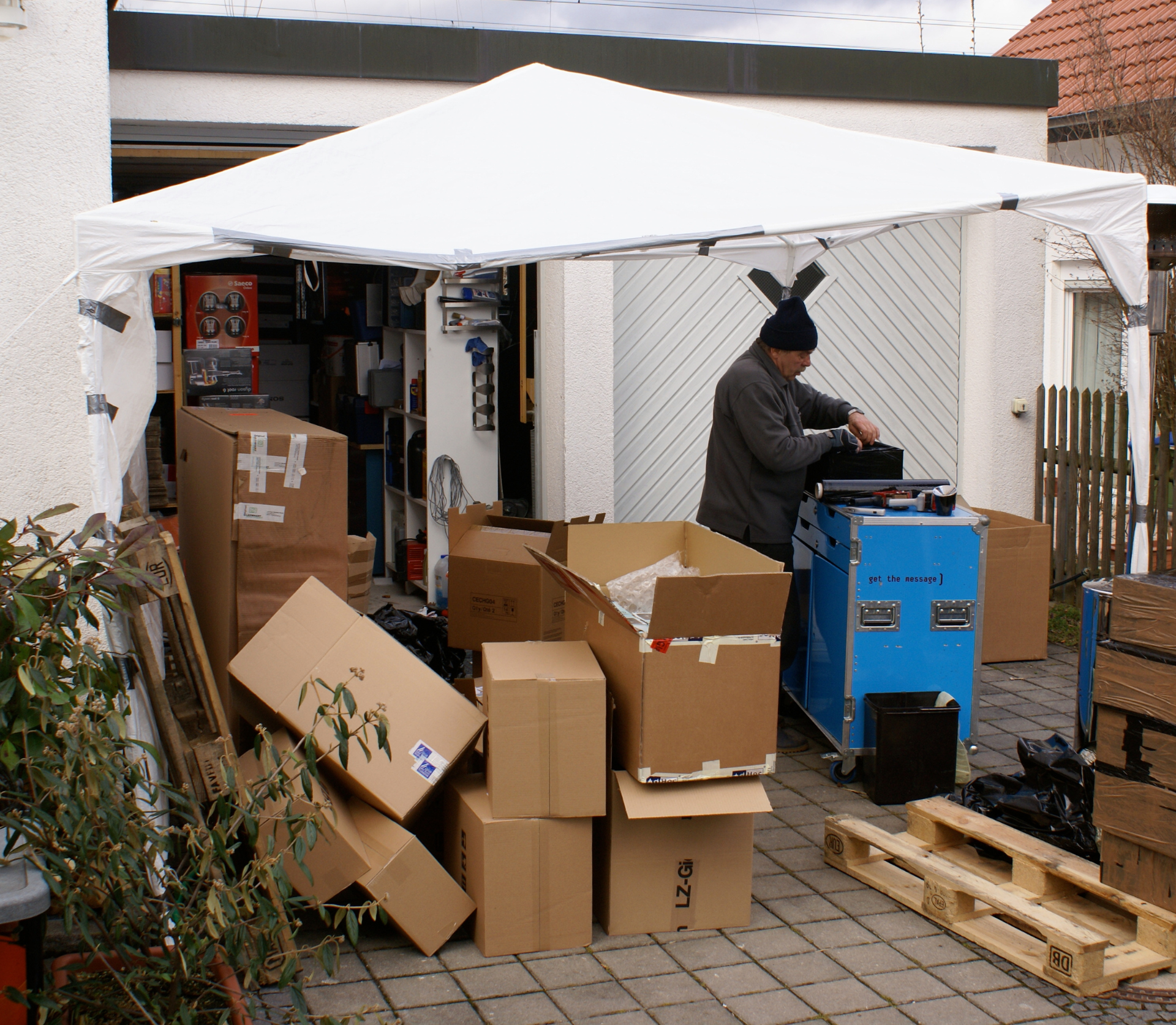 Packstation in Einfahrt: Garage mit Umzugskartons, Faltzelt und Palettenheber