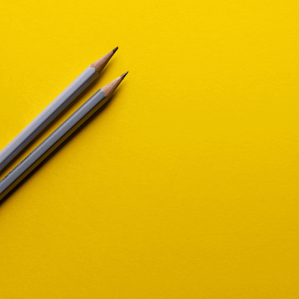 Minimalistische graue Bleistifte auf gelbem Hintergrund