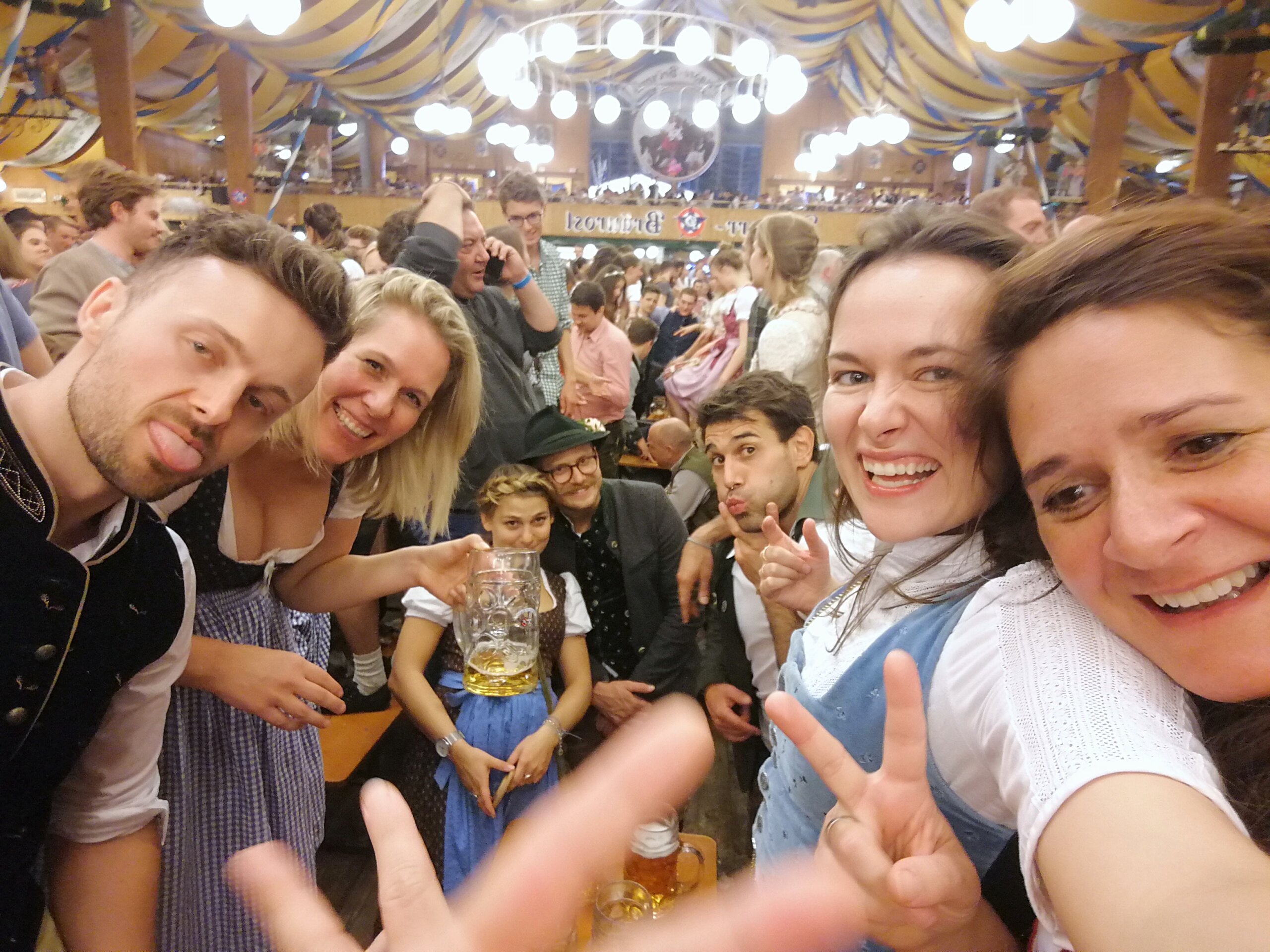 Festzelt-Selfie: lachende Freunde in Tracht mit Bierkrügen.