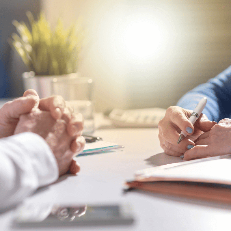 Beratungsgespräch: Hände mit Stift über Dokumenten im Büro