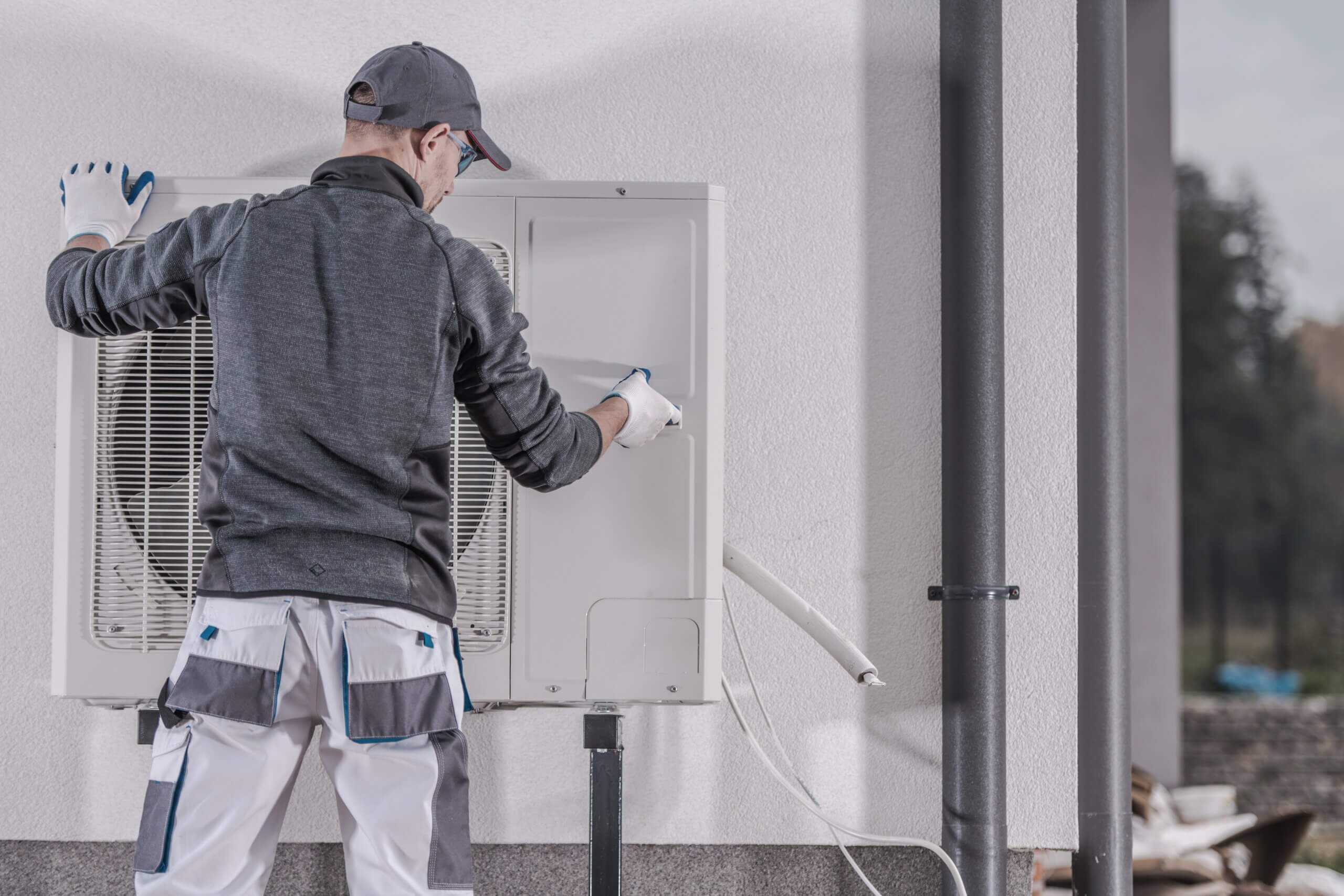Wärmepumpe-Wartung durch Techniker an Hausaußenwand