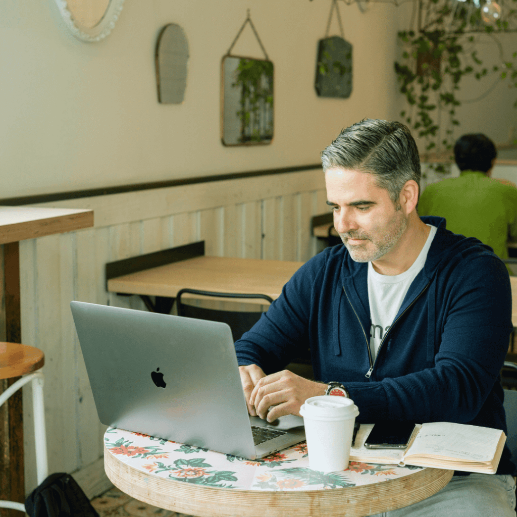Kundenbindung steigern: Mann arbeitet im Café am Laptop