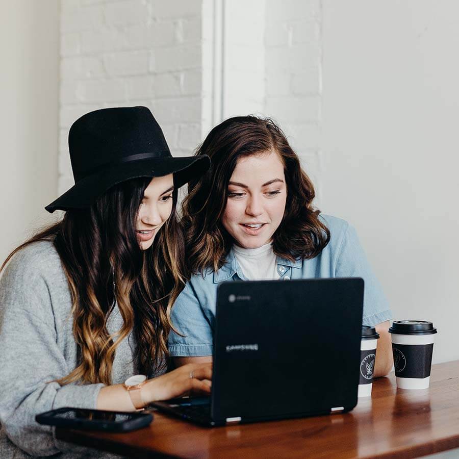 Zwei Personen bei Teamarbeit am Laptop mit Kaffee, konzentriert und kollaborativ.