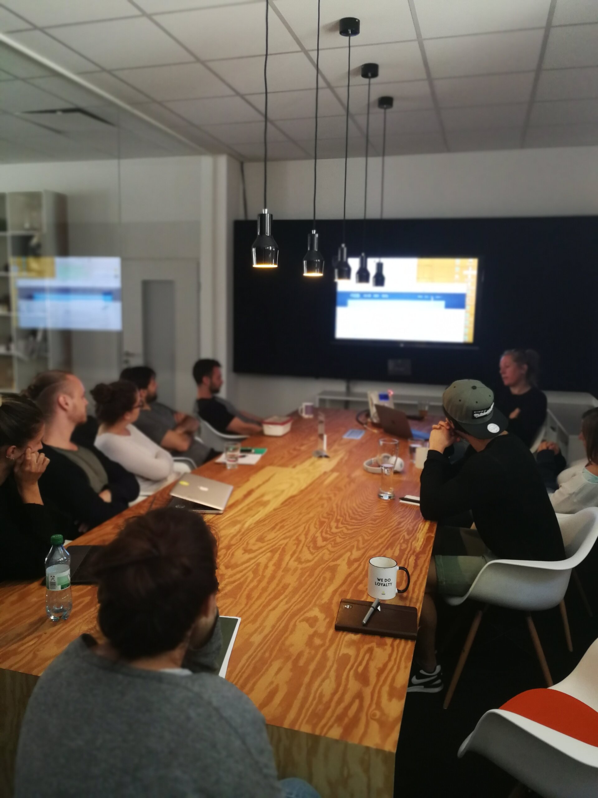 Teammeeting im modernen Konferenzraum mit Holztisch und Bildschirmpräsentation