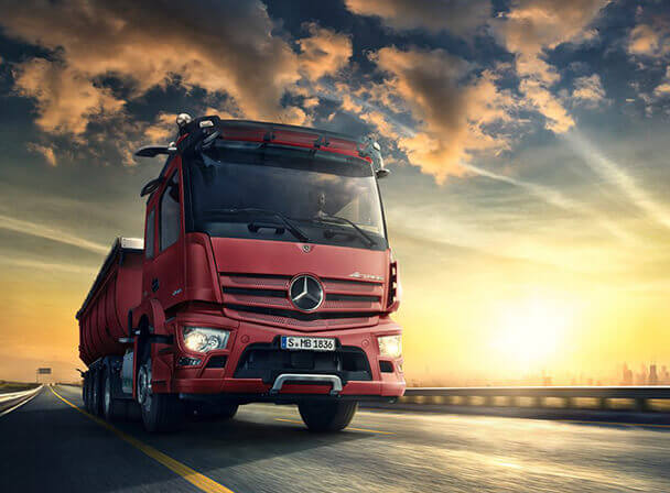 Roter Mercedes Lkw-Kipper auf Autobahn bei Sonnenuntergang