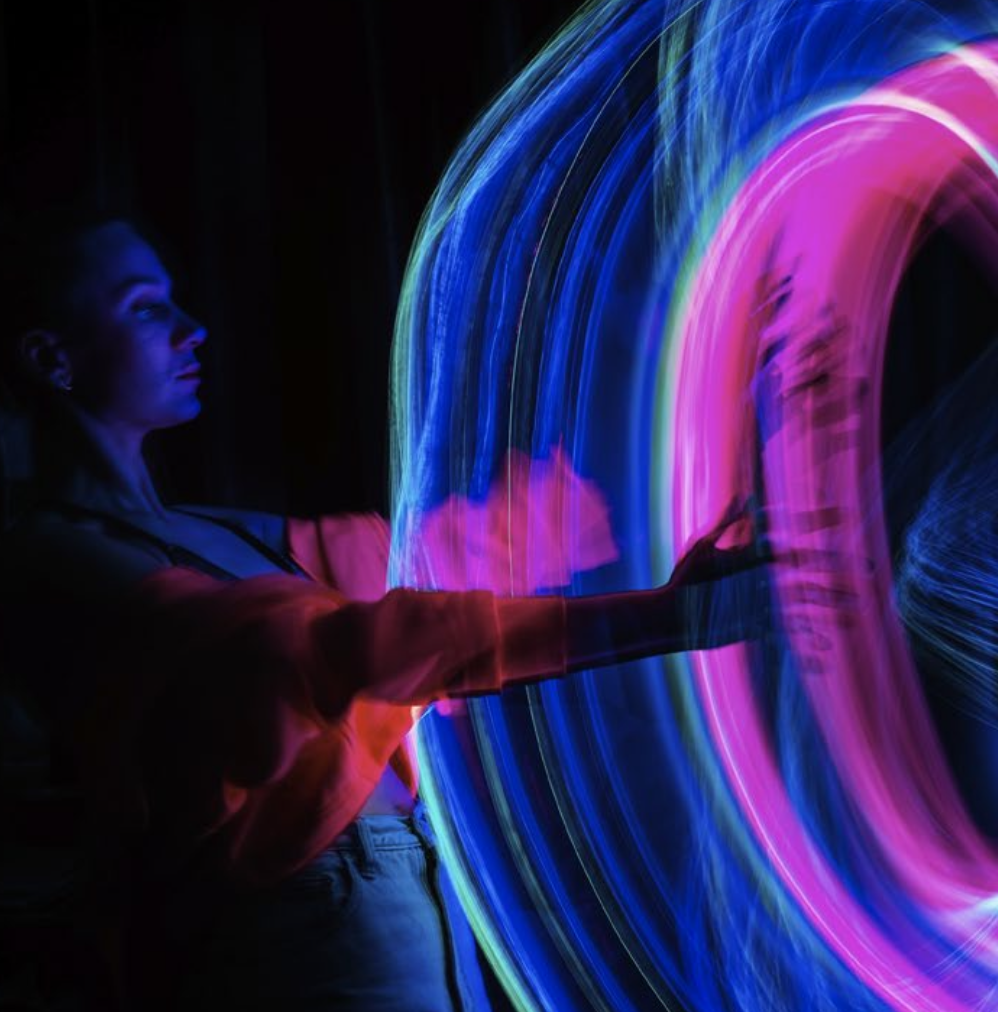 Person mit Neonringen aus blauem und magentafarbenem Licht