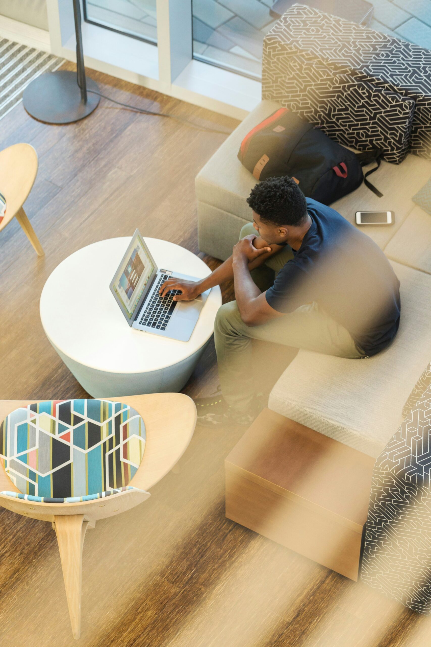 Home-Office: Person arbeitet mit Laptop auf Sofa in modernem Wohnzimmer